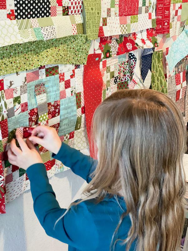 Lissa Alexander's granddaughter pinning blocks to design wall